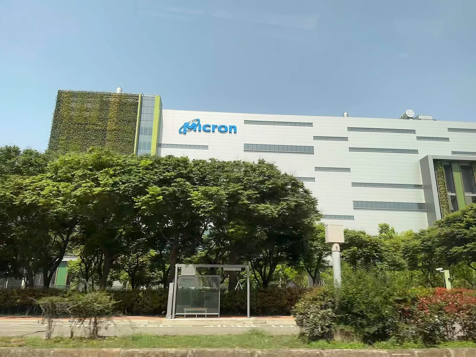 A modern factory building behind trees