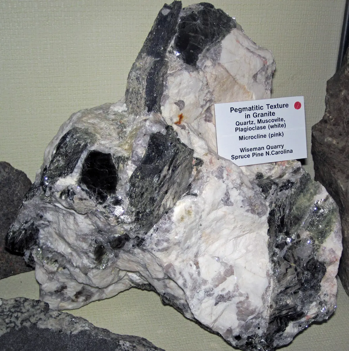 A coarse rock of white quartz and feldspar with dark crystals