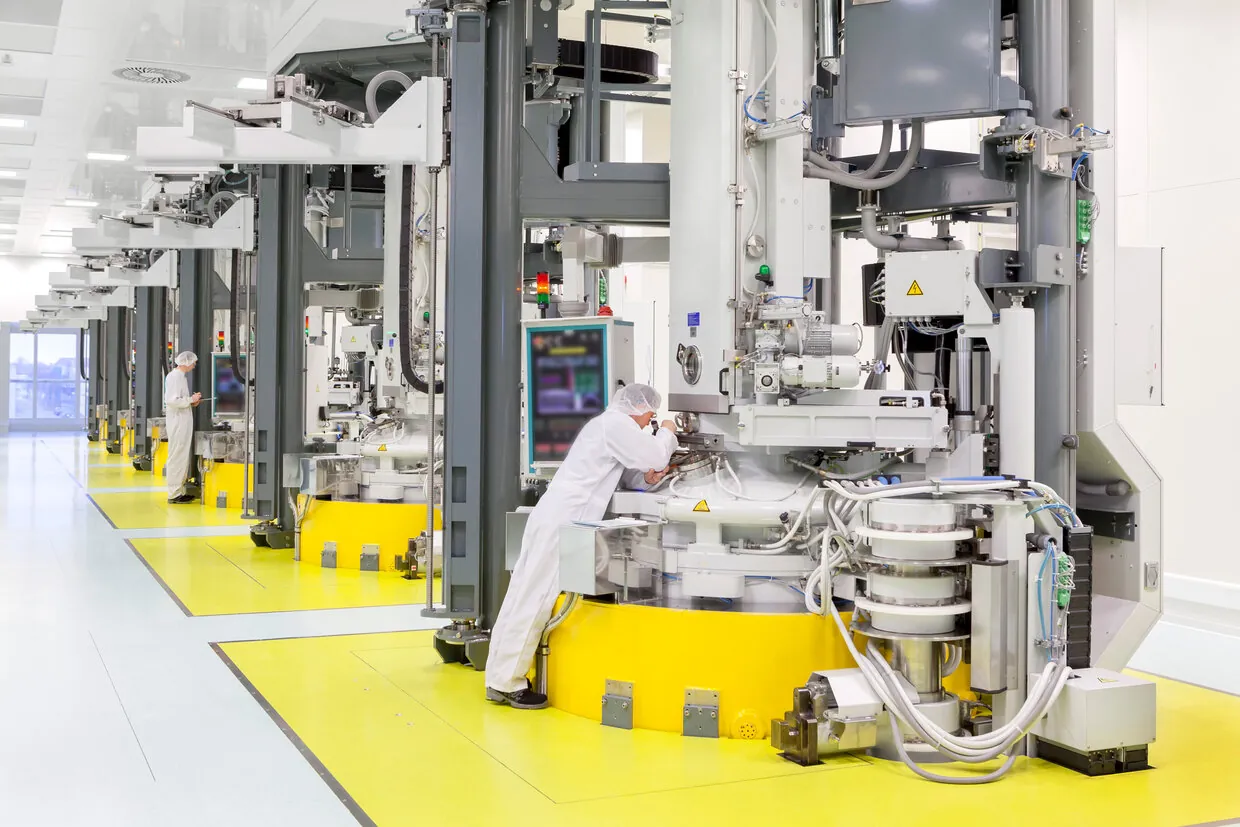 A row of tall crystal-pulling machines in a white cleanroom