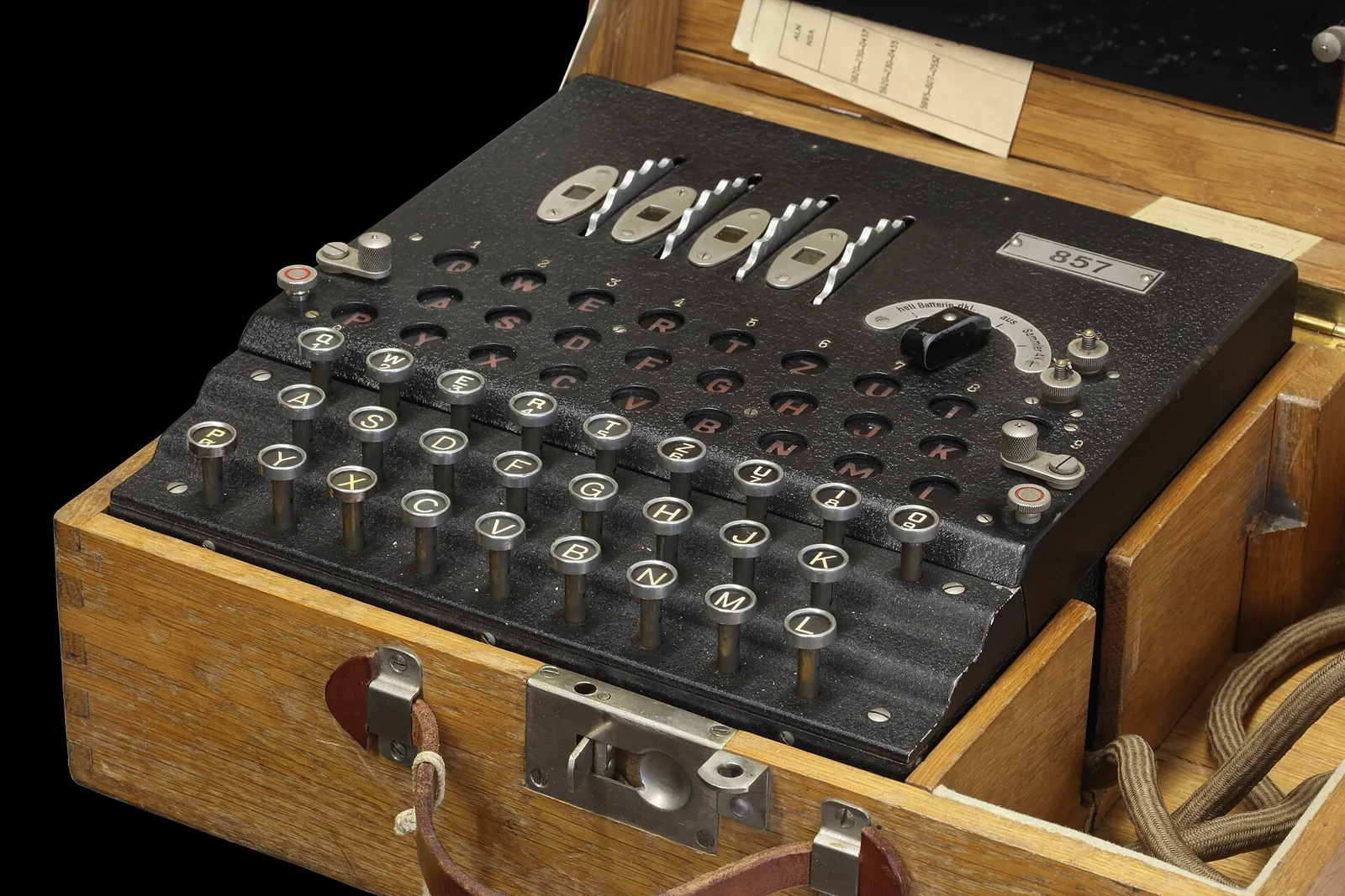 An Enigma cipher machine in an open wooden case, with keyboard, lamp board and rotors