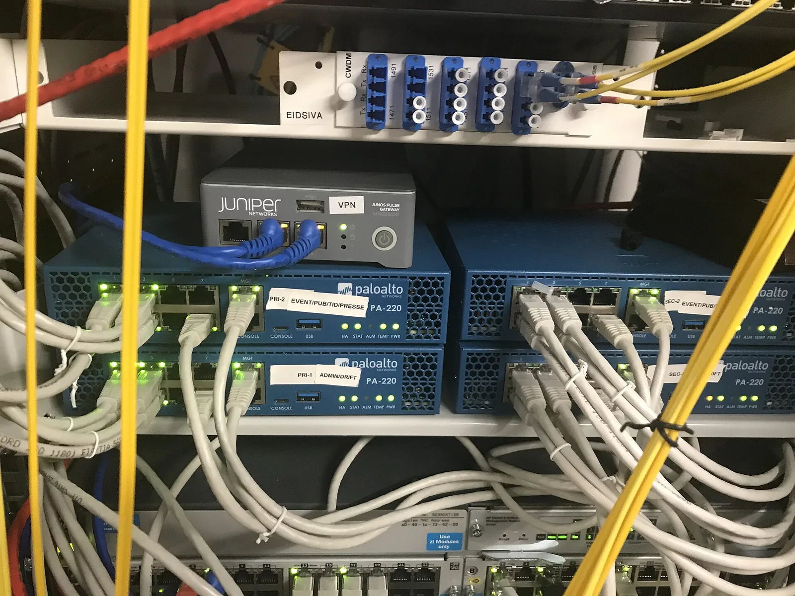 Small Palo Alto Networks firewall appliances and a Juniper device in a rack, with network cables plugged in
