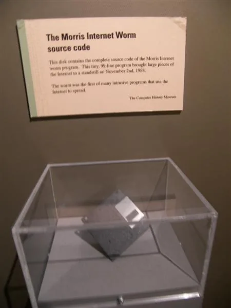 A black floppy disk in a clear display case with a museum label