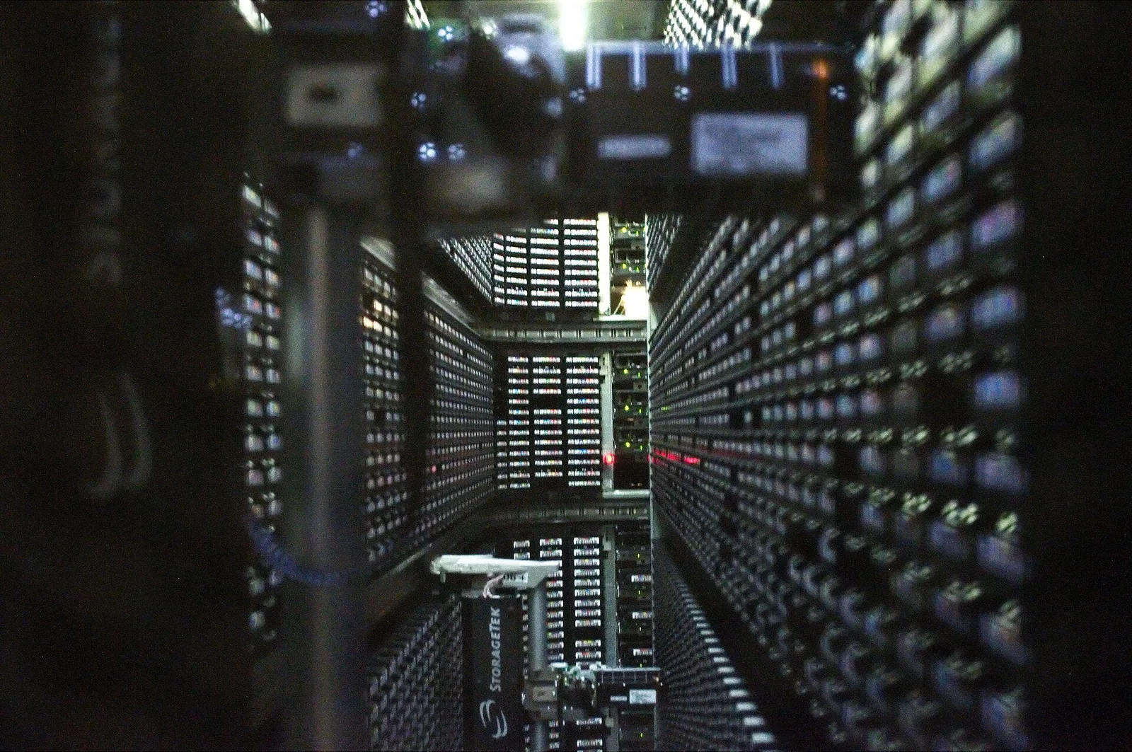 A long corridor inside a robotic tape library, lined with walls of tape cartridges