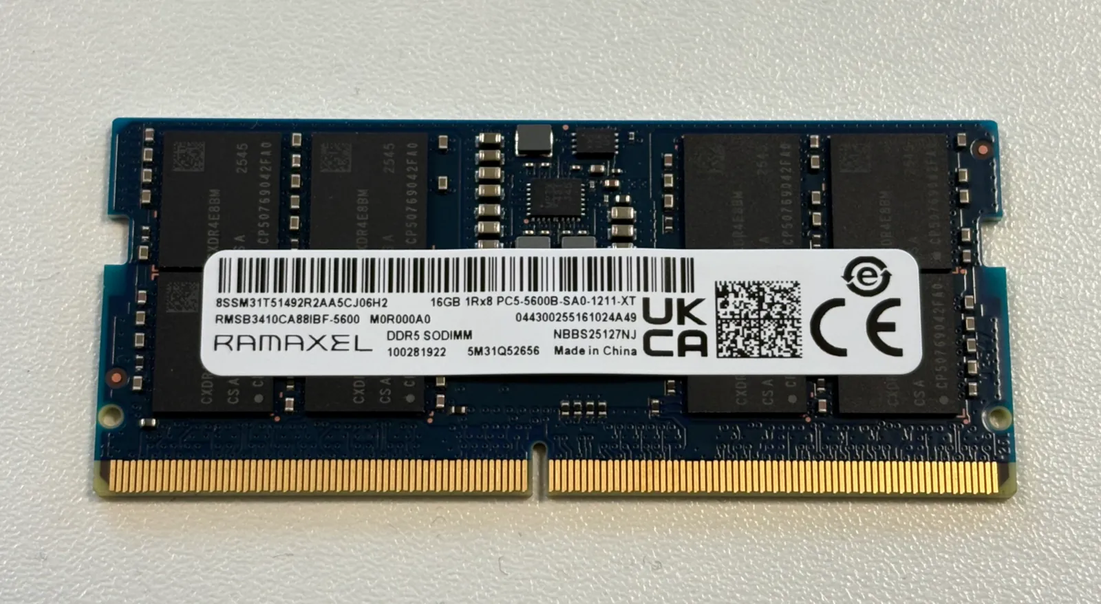 A green laptop memory module with a row of black chips and a white label