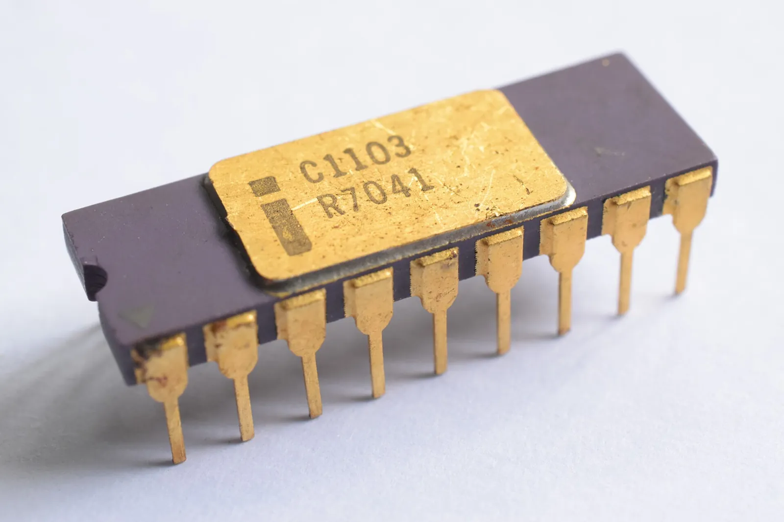 A ceramic chip with a gold lid marked C1103 and two rows of gold legs