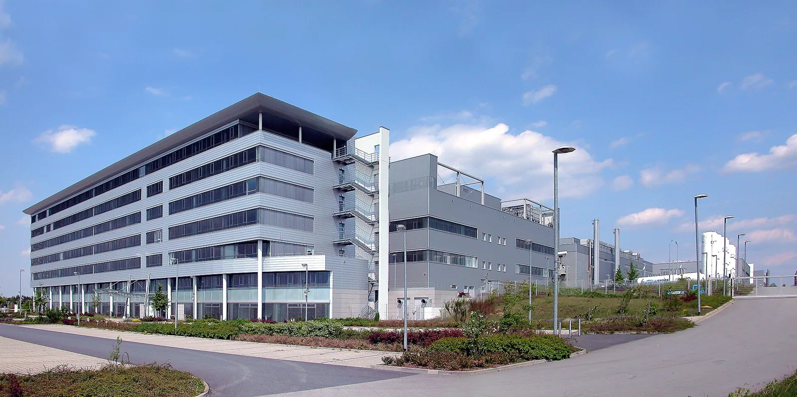 A long white factory building with a Qimonda sign, behind a road