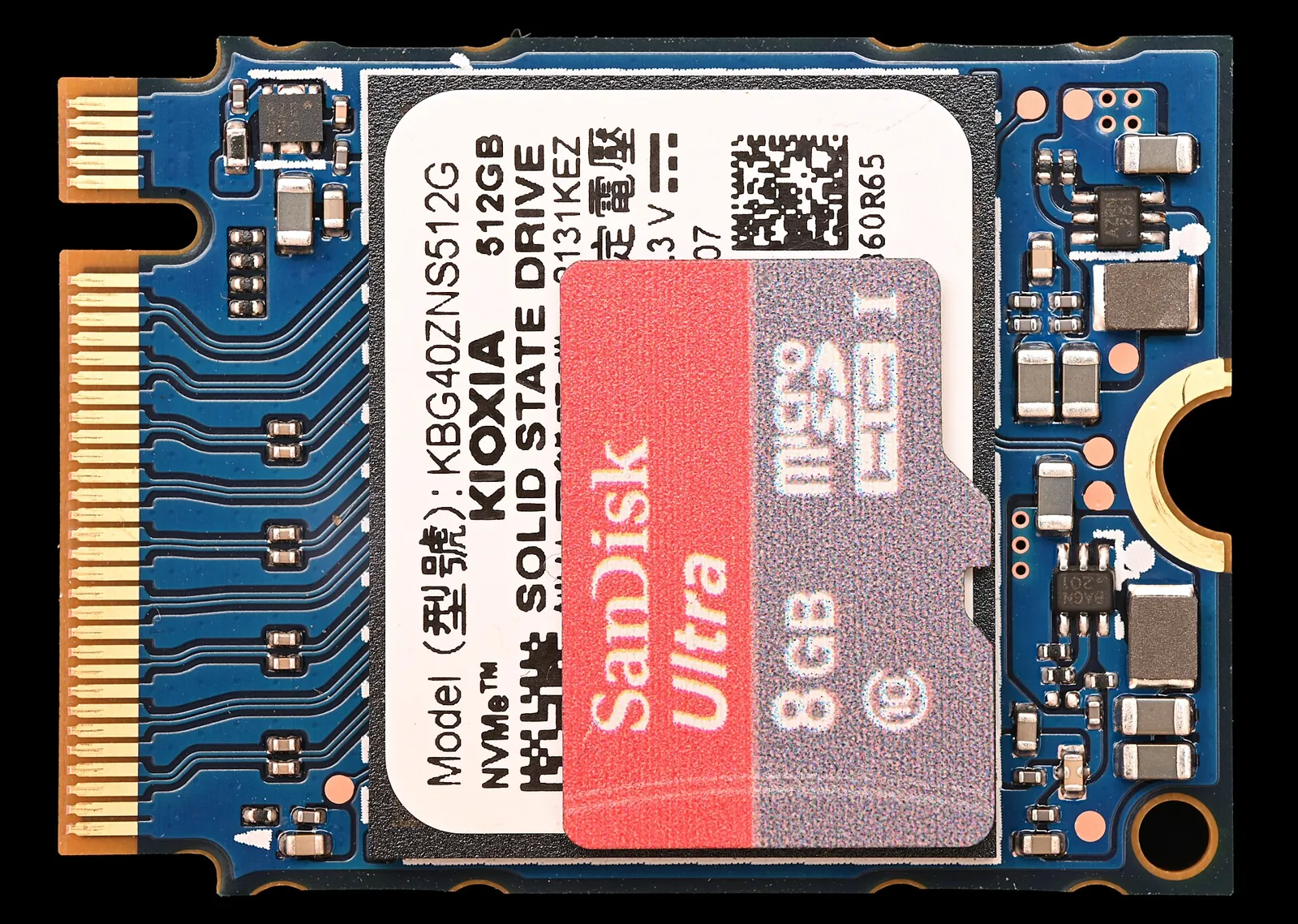 A small Kioxia SSD circuit board next to a SanDisk microSD card