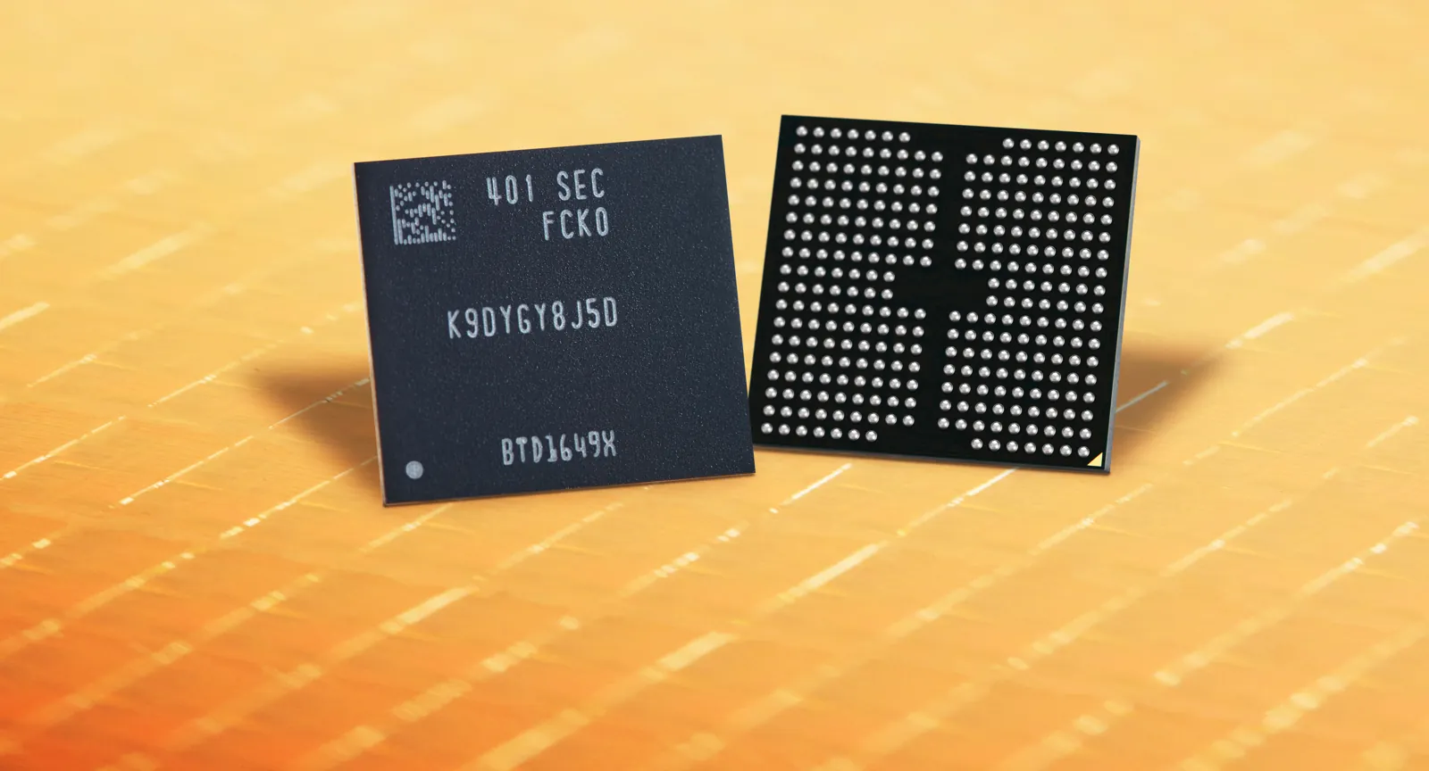 Two black flash memory packages, one showing its ball-grid underside, on a gold wafer background